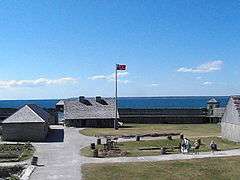 alt=Interior of a walled fort overlooking water, showing several buildings and walkways