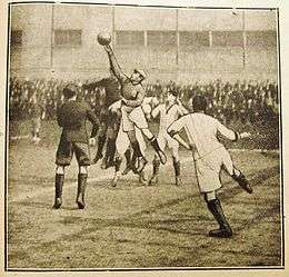 Old cartoon of an association football match with the goalkeeper in the middle who jumps and hits the ball