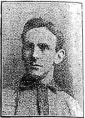 Head and shoulders of a young, clean-shaven man with dark hair parted on the left of centre. He is looking to his right, and is wearing a light-coloured sports shirt with dark collar and trim.