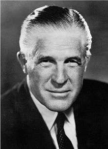 Headshot of a greying man in a suit who is directly facing the camera