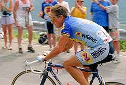 A cyclist, being watched by some spectators