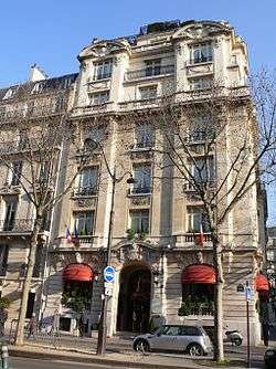 A six storey building at the corner of a terrace lined in front by bare trees