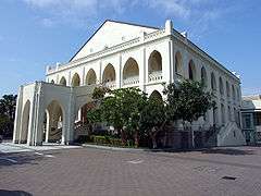 White, two-storied neo-gothic building with leading dual staircase