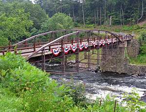 View of the bridge from the north, crossing a deep gorge, with curving trusses over and under