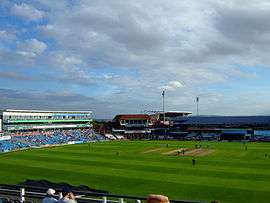 A panoramic view of a cricket ground with players occupying the field