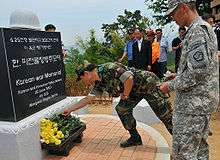 Soldiers lay roses at a large monument