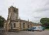 A large stone church seen from the northwest with battlemented parapets and pinnacles on the west tower and the body of the church