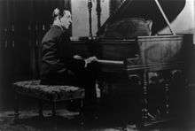 A man seated at a piano with his hands on the keyboard.