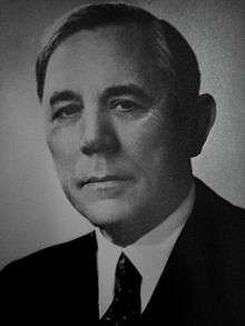 A black-and-white bust portrait of a distinguished man in a suit.