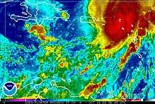 Colorized infrared satellite image of a hurricane. The storm, is in the top right portion of the image and has a poorly defined eye. A red mass, depicting strong convective activity, is present along the eastern side of the storm.