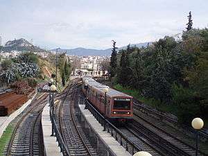 Same type of train passing evergreen trees