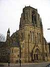 The west end of a Gothic Revival church with an elaborate broad tower