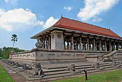 Long stone building with columns and a red roof