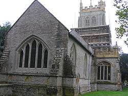 Stone building with arched window. Square tower surrounded by scaffolding.