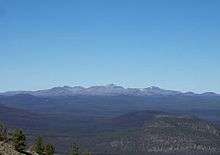 A large gently-sloped mountain rising above the surrounding area on a clear day