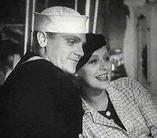 Cagney in a sailor suit with a smiling actress leaning on him.