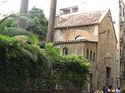 Church-like stone building, with vegetation along a tall iron fence