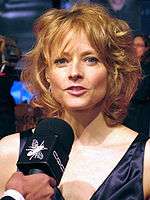 a close up image of a strawberry blonde haired woman wearing a purple dress.