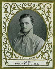 A black-and-white photograph of a curly-haired man wearing an old-style white baseball jersey with a high turned-up collar