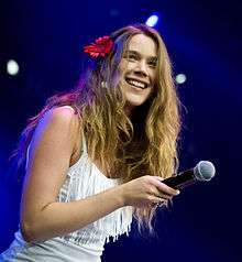 A girl wearing a white dress and a flower in her hair is performing