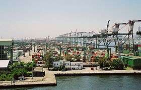 Harbor dock, with many rows of containers, and large cranes for loading on to ships.  The cranes are labeled 'Evergreen.'