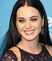 An image of a black haired woman, smiling and posing against a UNICEF backdrop