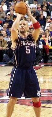 A man of mixed ethnicity (half white, half black) shoots a free throw during a basketball game.