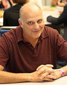 A smiling Caucasian man wearing a red polo shirt.