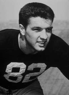 A football player in a tackling stance while wearing a dark jersey with the number 82 on it.