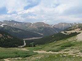 Several mountains with scars from roads visible at the base and up the sides