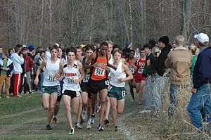 runners nearly colliding as they round a bend, as observers look on