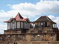 Two rectangular stone tombs, each topped with a small decorative wooden house