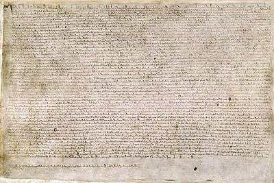 A photograph of a page of Magna Carta, a wide page of dense, small medieval writing.