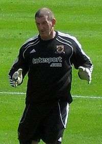 A man with brown hair who is wearing a black top.