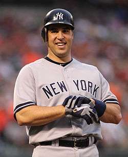 Mark Teixeira, wearing a dark blue baseball batting helmet and grey baseball uniform with the words NEW YORK across, takes off his batting gloves