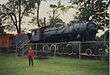 A woman standing in front of an antique steam locomotive