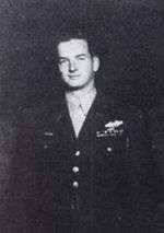 A black and white image of Michael Daly in his military uniform. He is standing and smiling