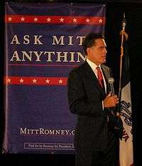 Mitt Romney addressing an audience from atop a stage