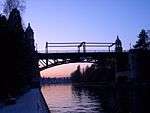 A bridge with Collegiate Gothic style towers over a canal at sunset