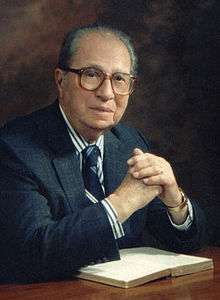 Middle-aged man sitting at a table over an open book