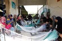 Women sitting in a circle, sewing fishing nets