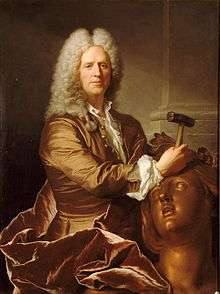 A portrait of sculptor Nicolas Coustou in full grey wig, his expression with a slight smile, and holding a hammer, with which he is working on the head of a large bronze female figure