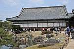 Wooden building with a large hip-and-gable roof and white walls.