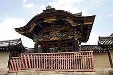 Black wooden gate with colorful ornamentation and a Chinese style gable on the front.