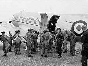 Uniformed personnel boarding a twin-engined transport plane