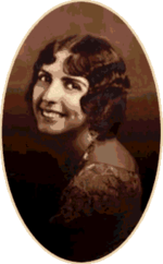 A studio photograph of a young woman looking over her shoulder.