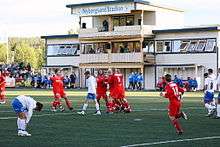 Two football teams in a stadium, the away team celebrating