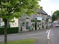 Stone building with sign saying The Old Pound Inn, on street junction.