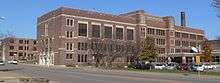 Large four-story brick building; other brick buildings around it