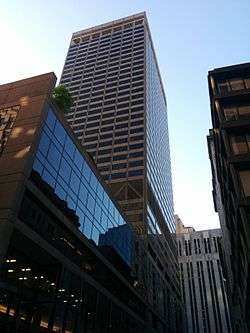 Ground-level view of a 38-story rectangular skyscraper with a tan facade and dark bluish windows